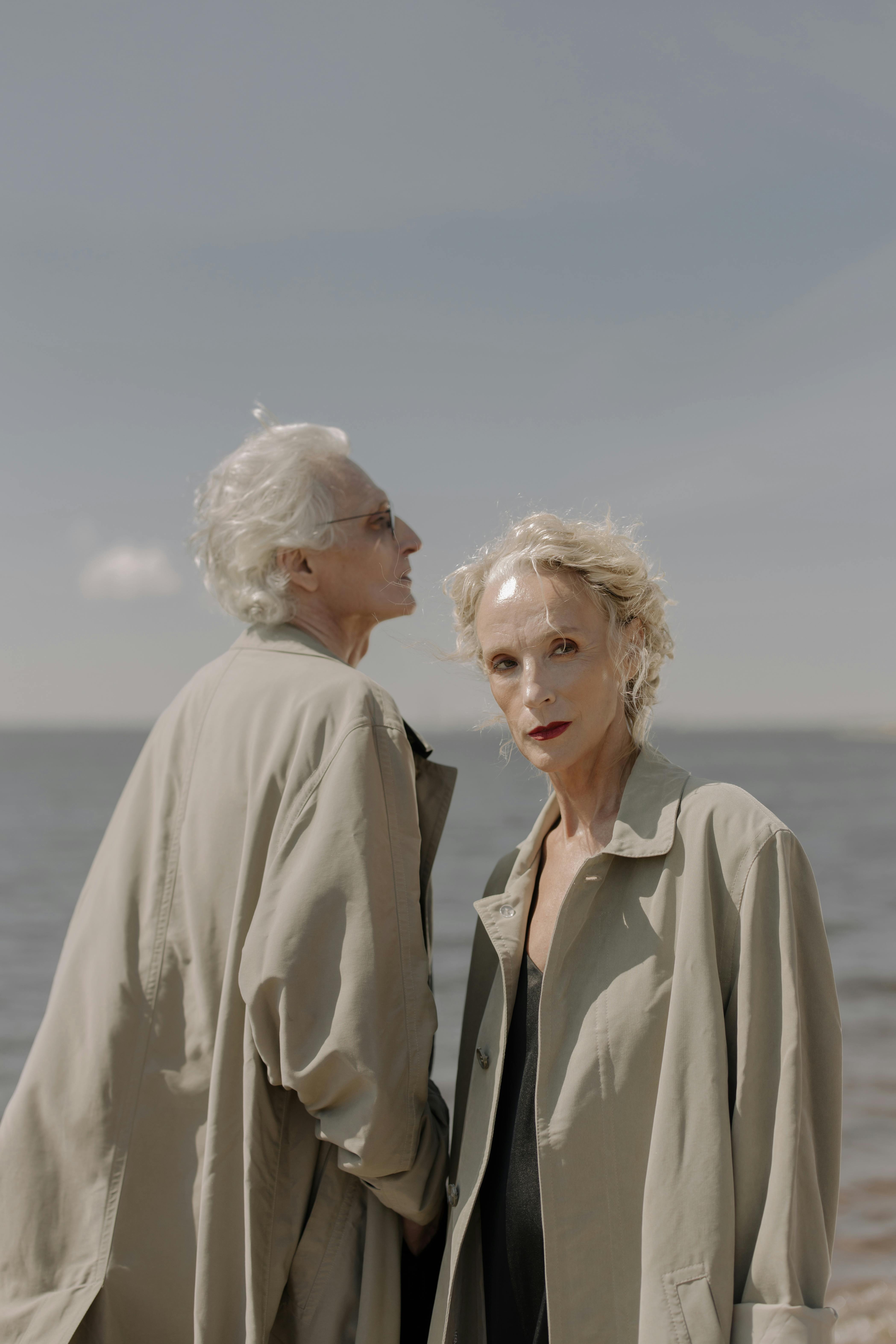 晴朗的日子里，两位穿着风衣的老人站在海边