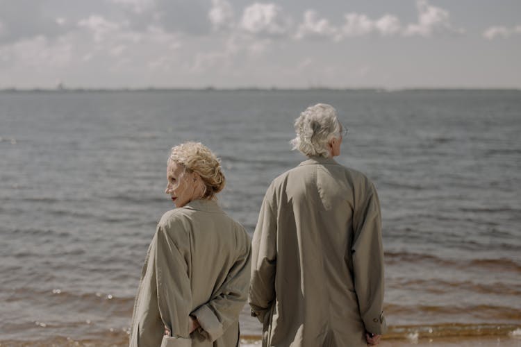 A Couple Wearing Trench Coats At The Beach