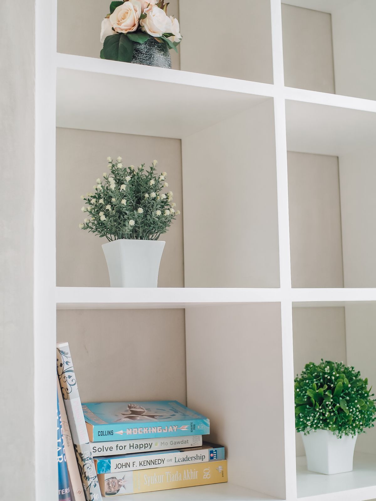 Elegant white bookshelf with potted plants and books in a minimalist room