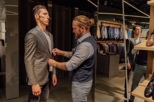 Free A tailor adjusts a man's suit jacket in a modern fashion store. Stock Photo