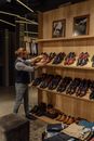一名男子正在一家时尚鞋店的木架上摆放豪华皮鞋