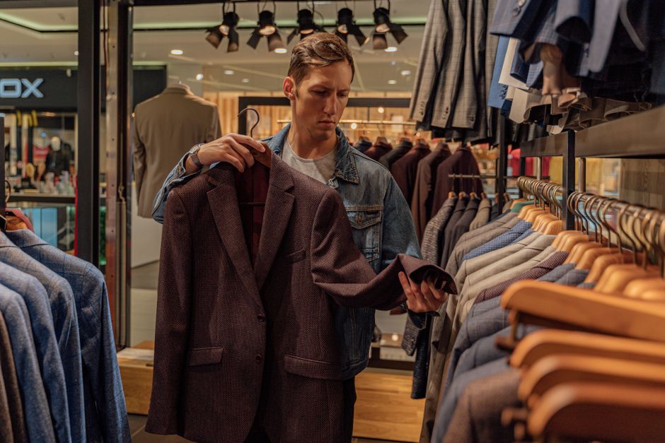 Man browsing stylish blazers in a modern clothing store, considering fashion options. Man browsing stylish blazers in a modern clothing store, considering fashion options.