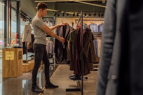 A Man Looking at a Suit Jacket in a Clothing Store · Free Stock Photo