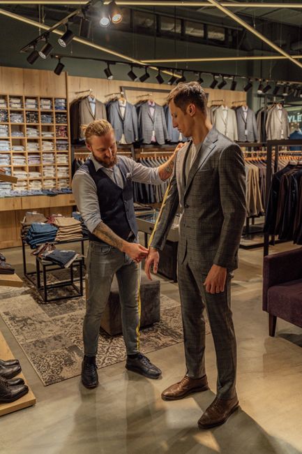 Professional tailor measuring client for a perfect custom suit fit in upscale clothing store. Professional tailor measuring client for a perfect custom suit fit in upscale clothing store.