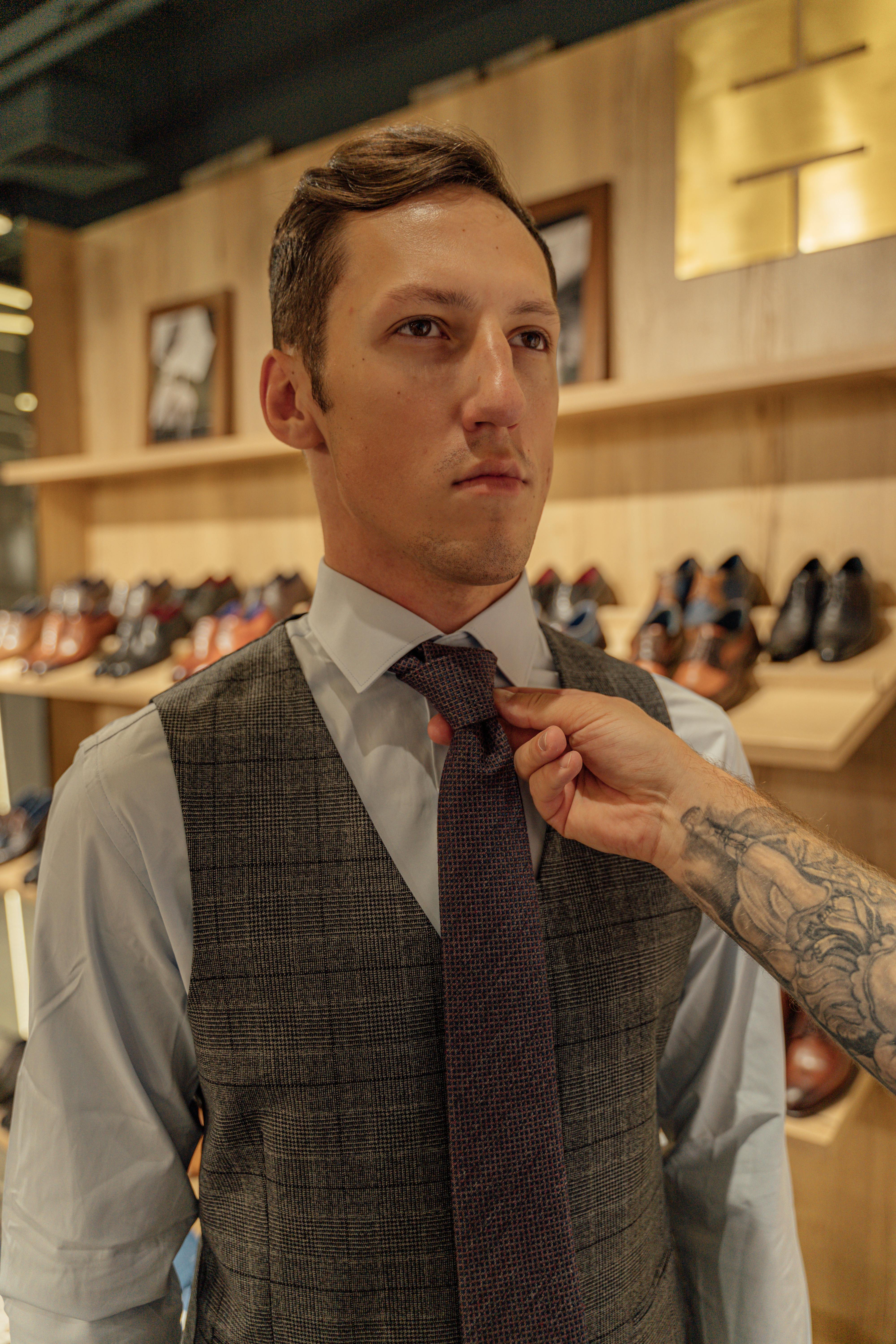 一名男子在一家时尚鞋店里整理领带，体现了时尚与风格的概念