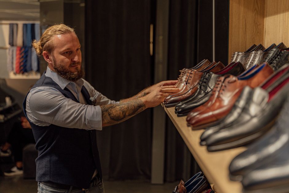 Adult man browsing leather shoes at an upscale store, exploring men's fashion options.
