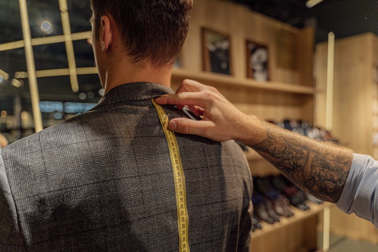 A Tailor Measuring A Man's Back Using A Tape Measure