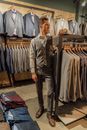 一位时尚男士正在服装店里，从摆满各种优雅选择的货架上挑选一套量身定制的西装