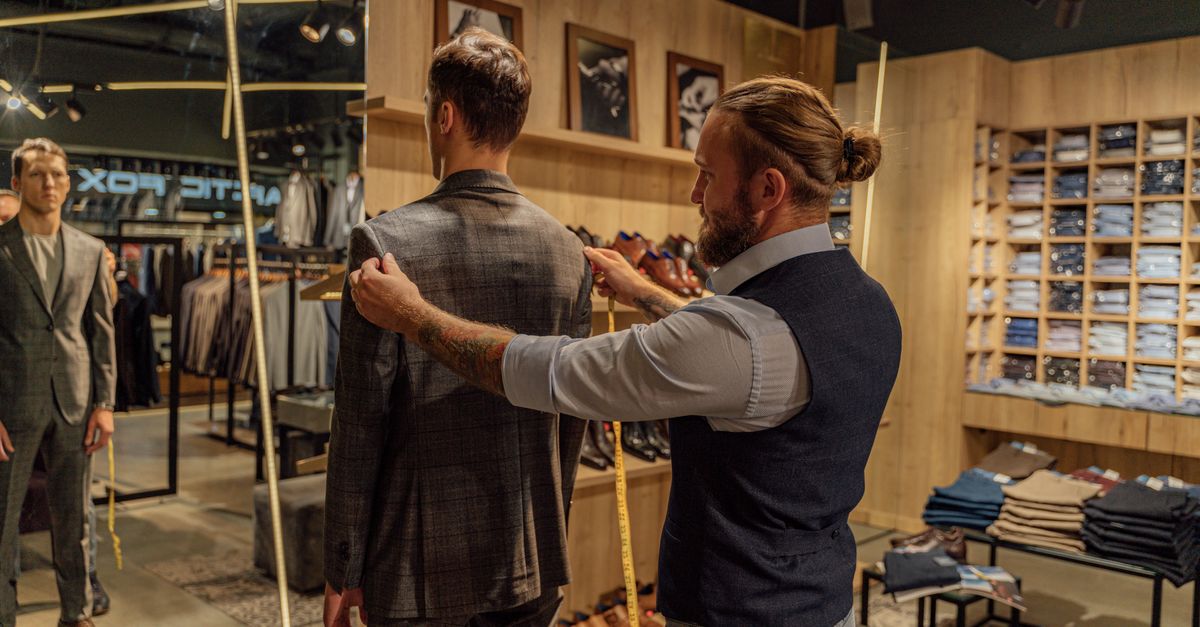 Tailor measuring a client in a clothing store, tape held to the body