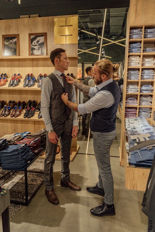 A Tailor Assisting a Man Fitting a Vest and Necktie