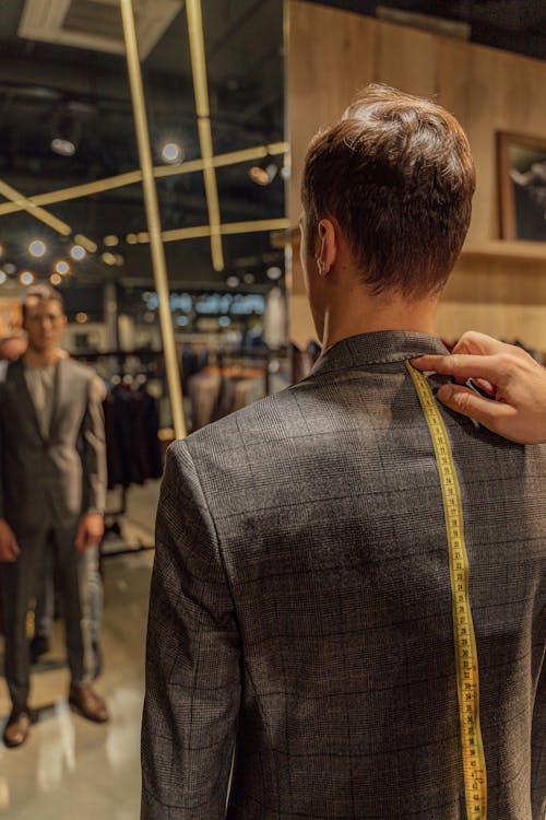 Hand of a Person Measuring a Man's Checkered Blazer