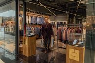 一名男子在一家现代服装店里展示购物袋，呈现时尚选择
