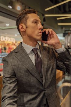 一位穿着灰色西装的自信商人正在时髦的室内环境中打电话