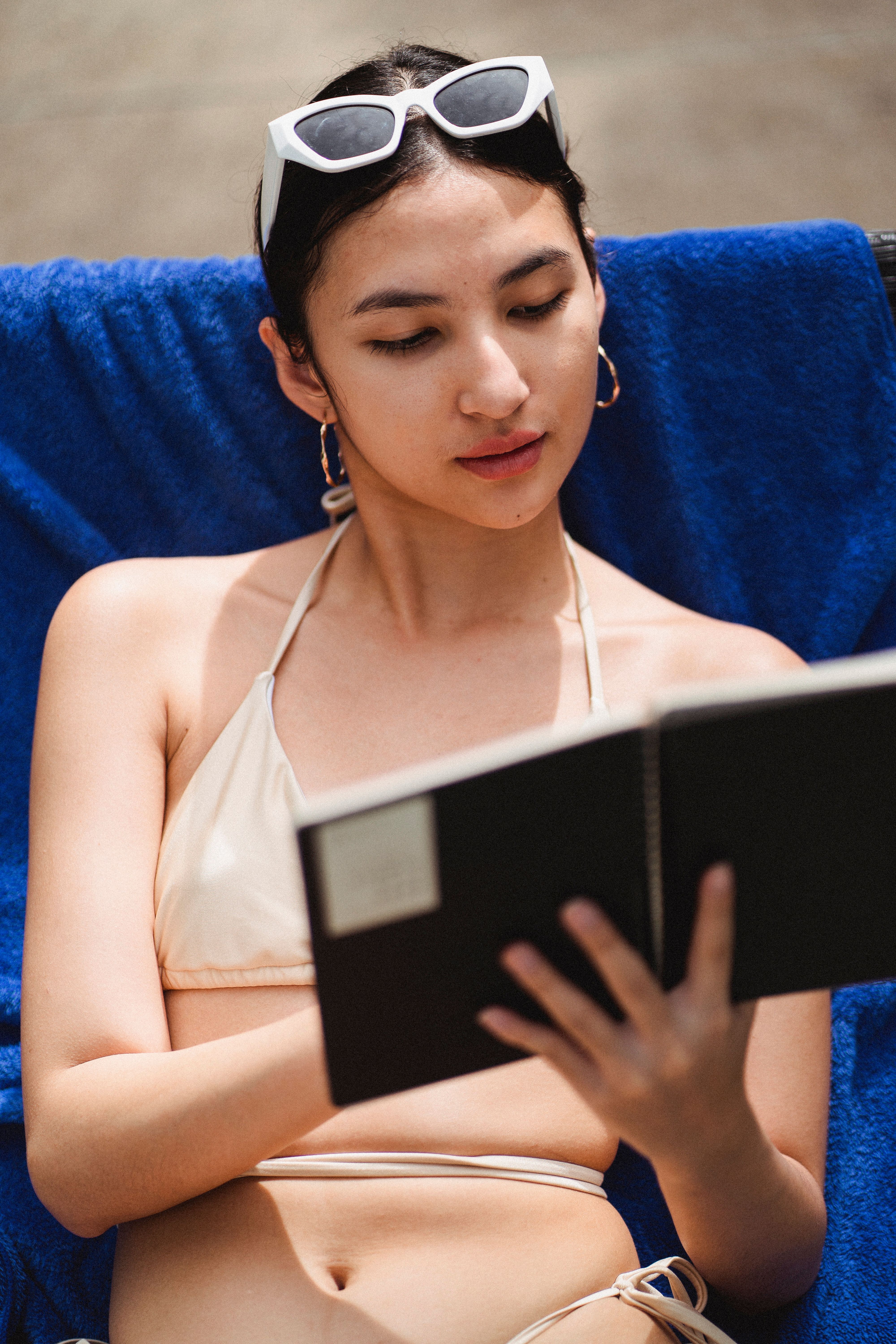 一位年轻女子喜欢在阳光明媚的日子里穿着比基尼在户外读书