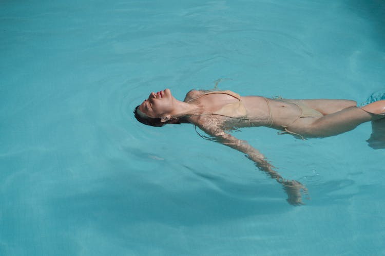 Slim Woman Swimming Backstroke In Swimming Pool