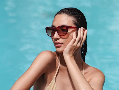 Stylish woman chilling in pool and touching face