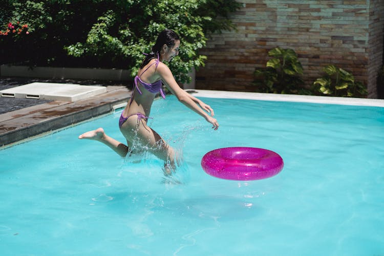 Happy Young Fit Woman Splashing Water In Swimming Pool After Jump