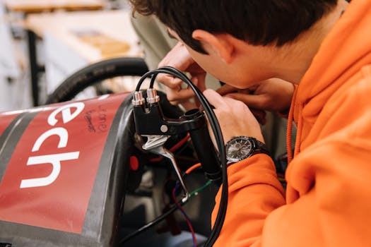Teenager focusing on an electric car project in a modern engineering workshop, showcasing STEM education.