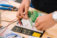 Hands of a Person Holding Wires on a Breadboard