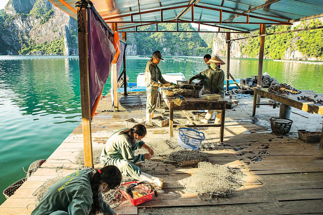 people-making-fishnets-on-a-wooden-pier