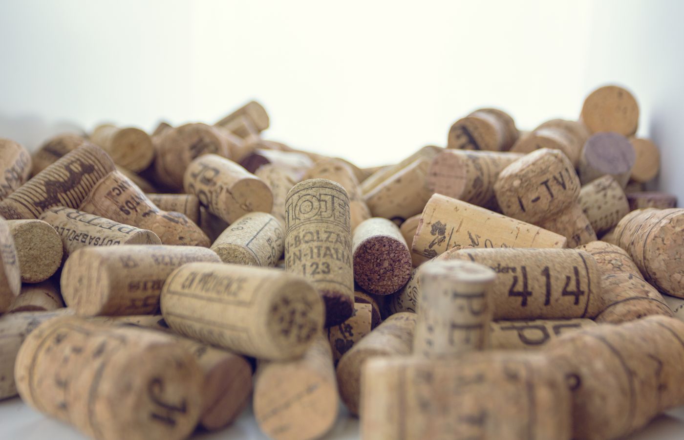 An artistic close-up of a collection of vintage wine corks arranged in a pile, showcasing various labels and textures.