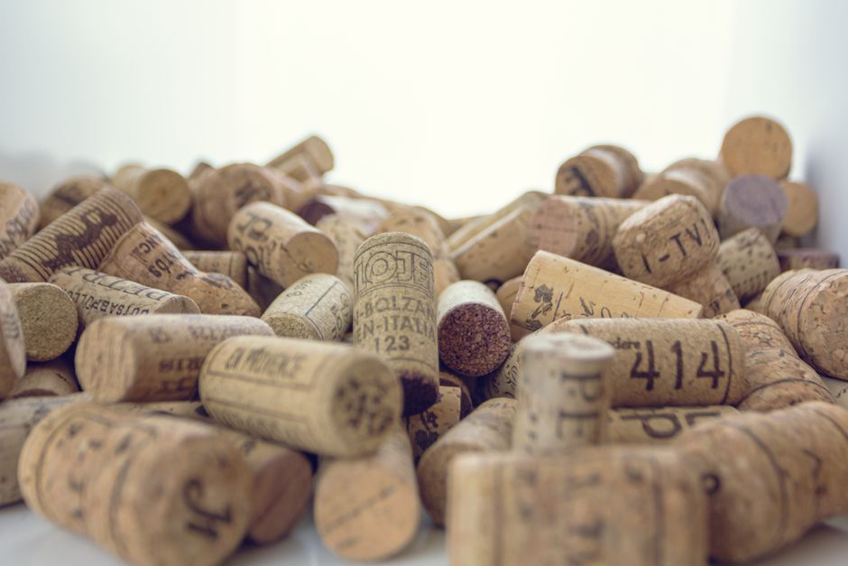 An artistic close-up of a collection of vintage wine corks arranged in a pile, showcasing various labels and textures.
