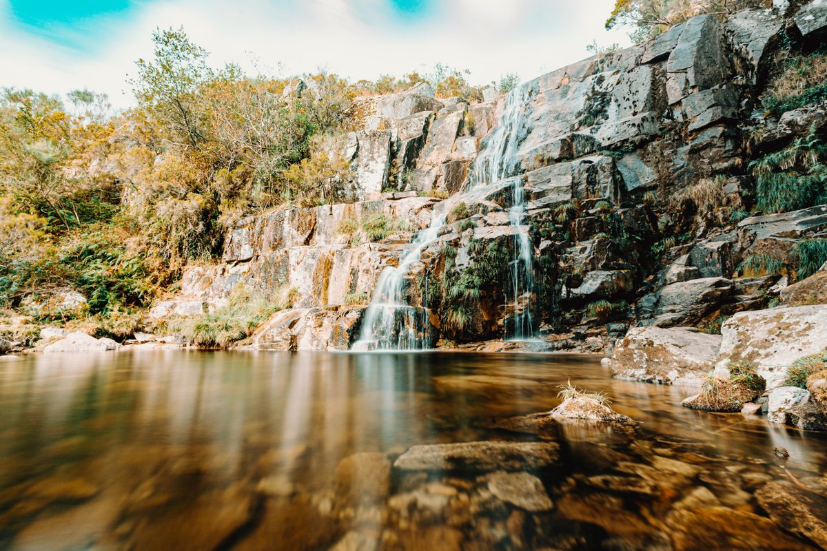 A tall waterfall in a valley under a blue sky