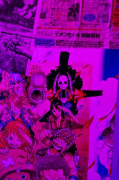 Cut pages with illustrations and text from magazines glued to wall and illuminated by neon light