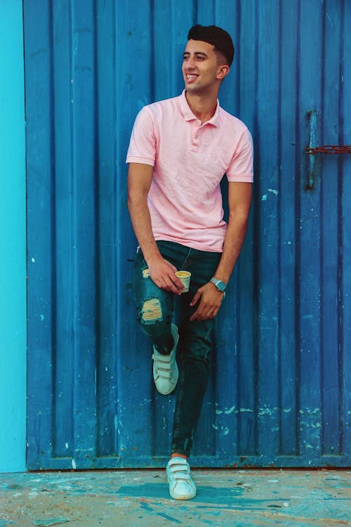 Man in Pink Polo Shirt Leaning on Blue Gate