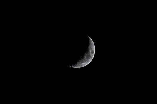 A detailed crescent moon illuminates a dark night sky, captured over Morocco.