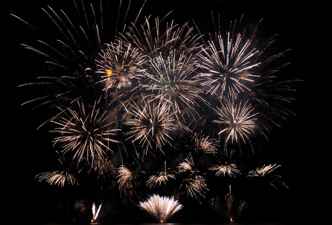 Free Abstract of vibrant glowing fireworks exploding high in black sky late at night Stock Photo