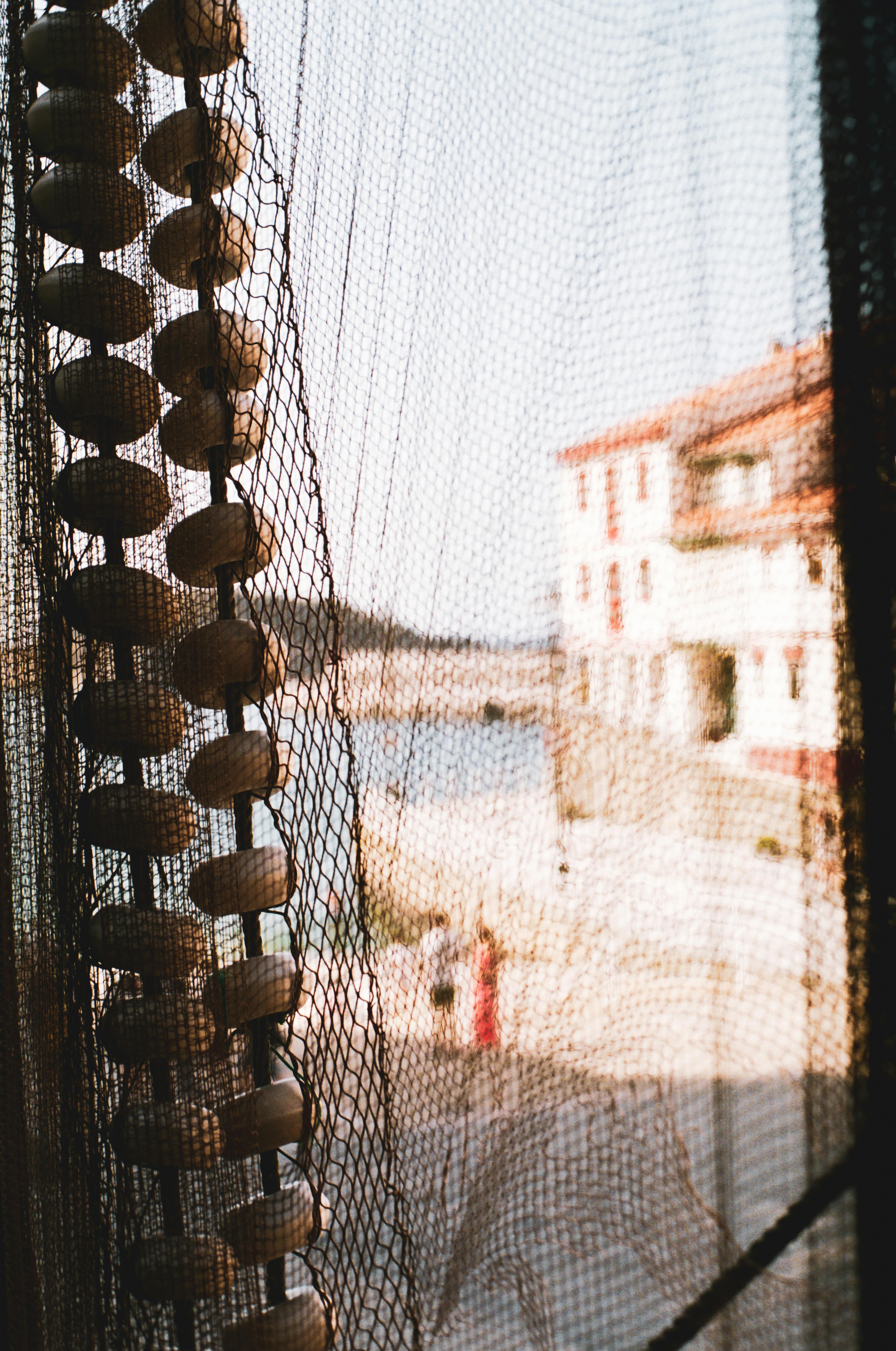 Close-up of a fishing net with Cudillero harbor in the background, capturing a coastal vibe.