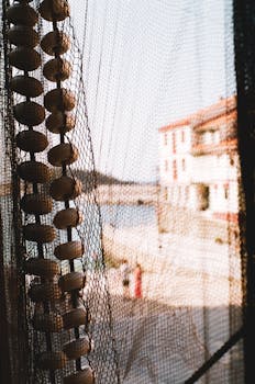 Close-up of a fishing net with Cudillero harbor in the background, capturing a coastal vibe.