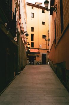 Beautiful narrow alleyway in Madrid's historic district with street lamps and charming architecture.