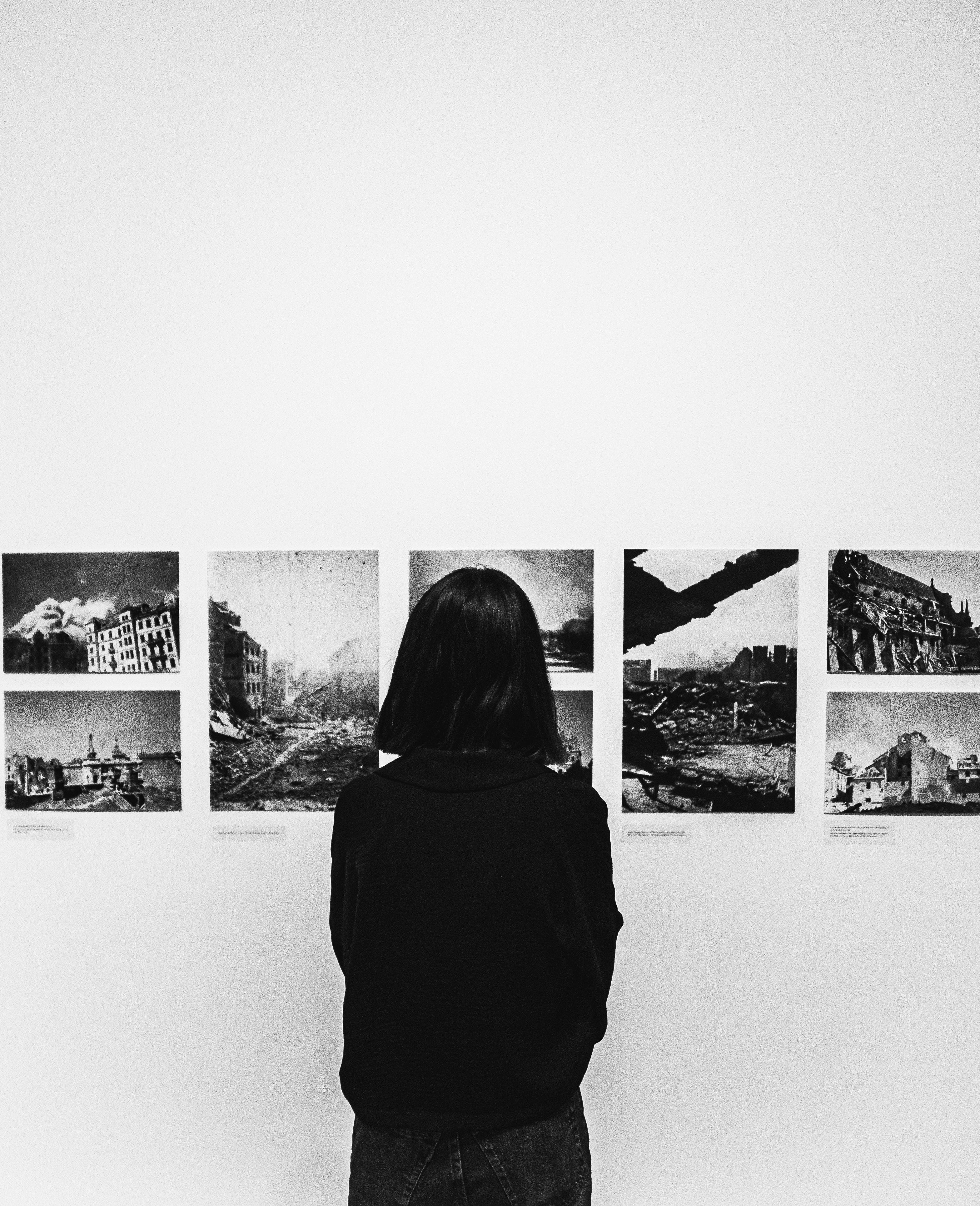 Black and white image of a woman viewing historical photographs in a Kraków museum.