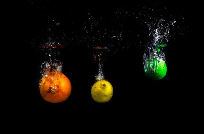 Colorful citrus fruits creating a dramatic splash underwater