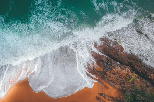 阳光明媚的海面上，泡沫般的波浪冲刷着岩石和沙滩