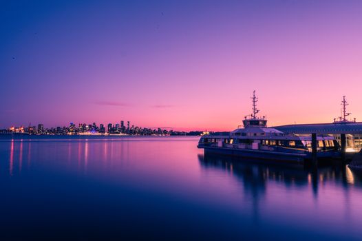 Serene twilight view of a docked ferry and Vancouver skyline across calm waters.