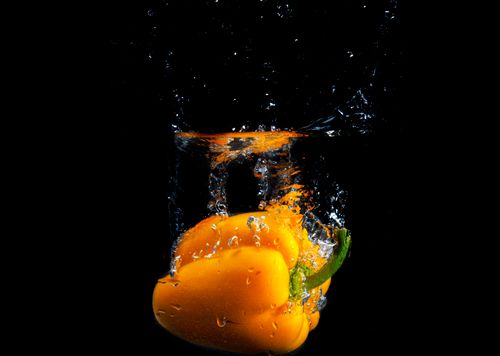 Free Yellow bell pepper splashes underwater, creating vibrant and fresh imagery. Stock Photo