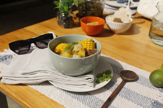 Delicious corn and vegetable soup served on a sunlit table, perfect for a healthy meal.