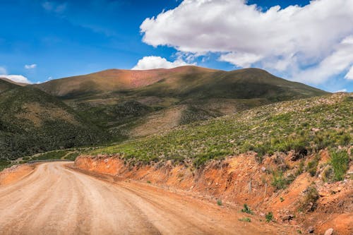 Brown Dirt Road Near by the Mountain Under Blue Sky