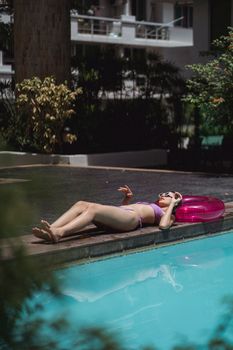 Side view full body of barefoot female traveler lying on swimming circle near clean water of pool