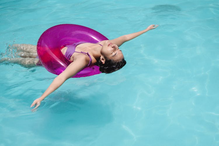 Calm Woman Swimming In Pool With Swimming Ring At Resort