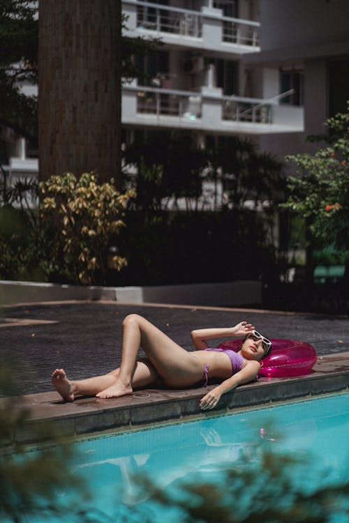 Young woman relaxing on poolside near hotel at resort