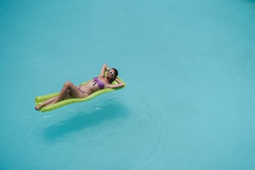 Slim female in stylish bikini resting in pool