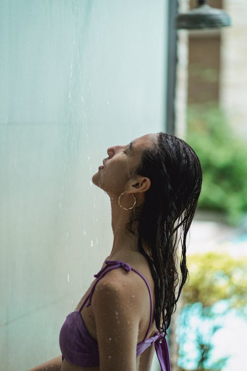 Young female with wet hair relaxing in shower
