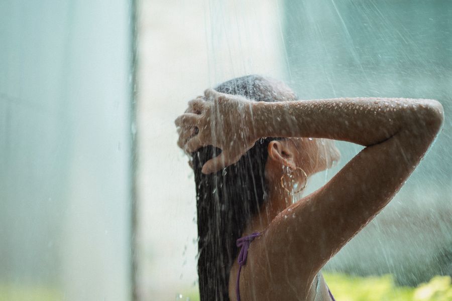 Woman washing hair in shower — hard water effects on hair