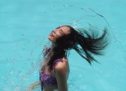 Slim waving hair in blue water of resort pool