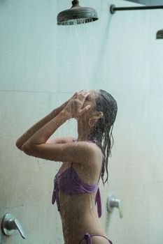一名年轻女子身着泳衣，在室内享受清爽的淋浴，进行自我护理和放松