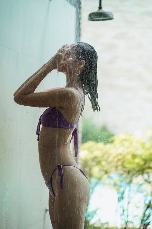 Slim sensual lady taking shower in resort poolside